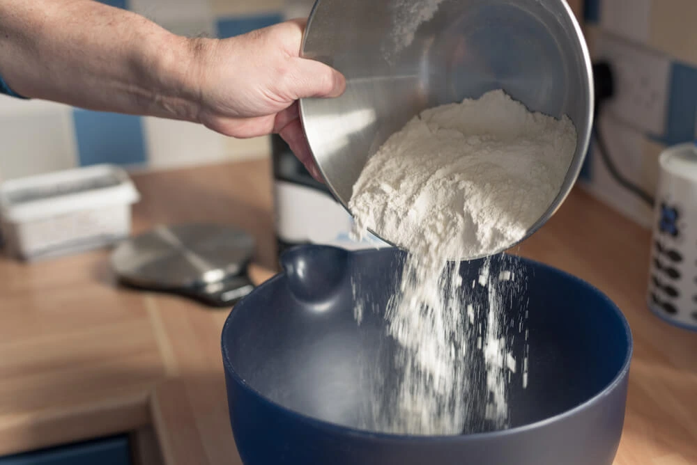 person pouring flour in a bowl