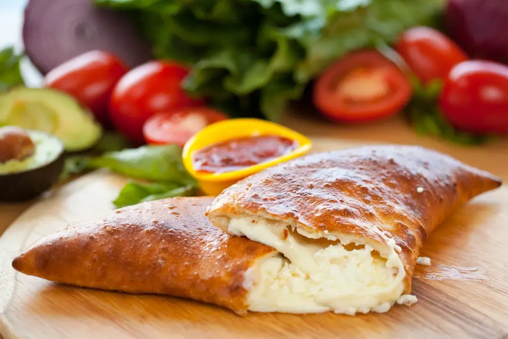 closeup view of a cheese calzone kept on a wooden surface