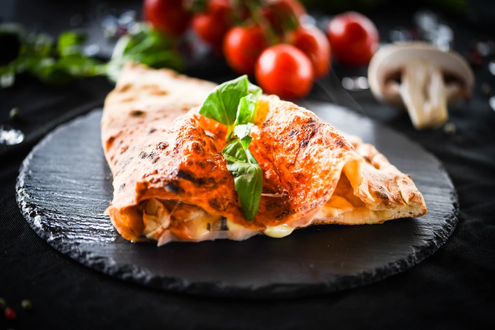 closeup view of pizza calzone in a black plate
